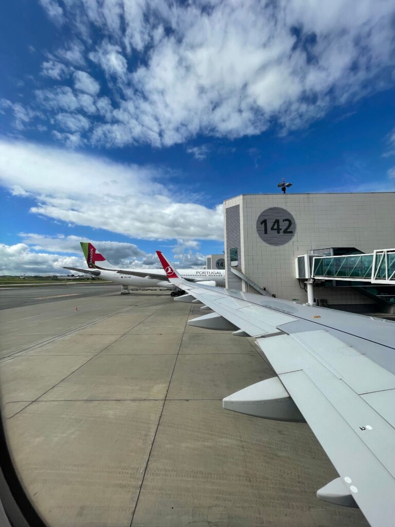 Airplane wing view at the airport gate, clear blue sky above. Ideal for travel and aviation themes.